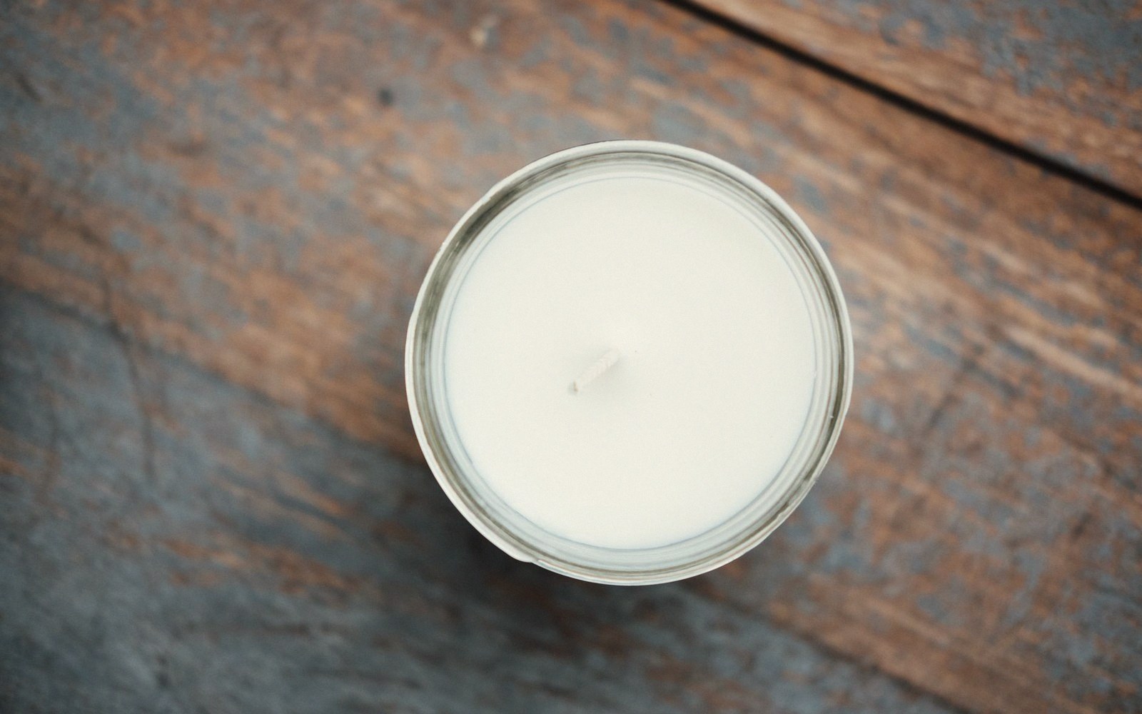 Overhead view of an unlit candle with a centered wick in a glass jar